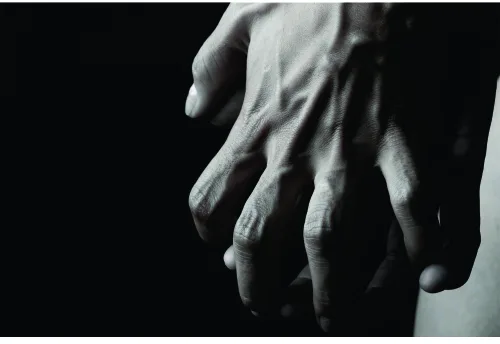 Photographic image of two pale hands reaching downward against a black background, rendered in monochrome with dramatic shadows.