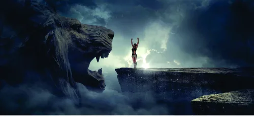 A solitary figure with raised arms stands on a rocky cliff, facing a massive stone creature looming through swirling mist under a dramatic cloudy sky.