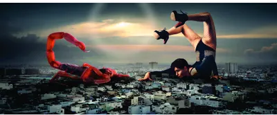 A photograph showing a giant red octopus rising above a cityscape with a person in athletic pose on a rooftop against a cloudy sunset sky.