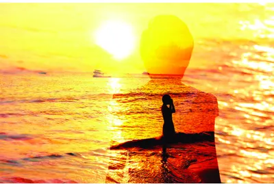 A silhouetted person stands on a beach facing a glowing sun reflected in wet sand, rendered in warm yellows, oranges and deep shadows.