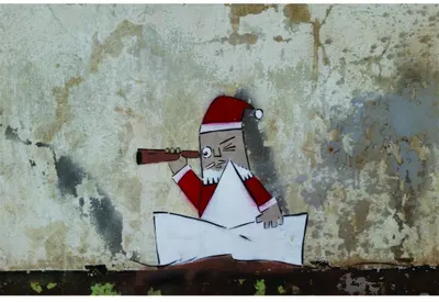 A cartoon Santa in red and white with a telescope, studying a large unfolded map beneath him against a weathered grey wall.